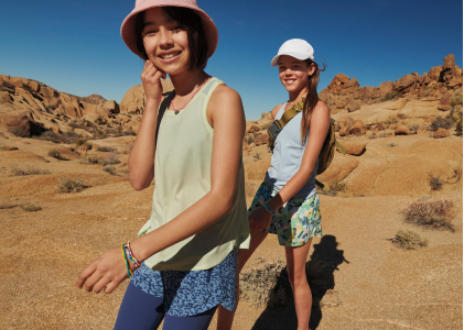 Two hikers trek across a desert landscape, clear blue sky above them.