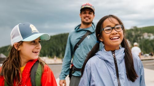 Two smiling children and a parent hiking in Yellowstone