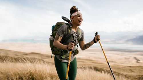 A hiker laughs as she makes her way across a golden field