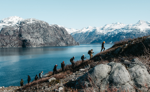 A group of hikers hiking up hill near a lake.