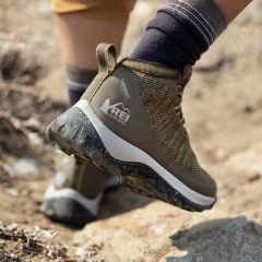 Close up of cushioned sole of REI Co-op hiking boot, worn by a hiker on a rocky trail