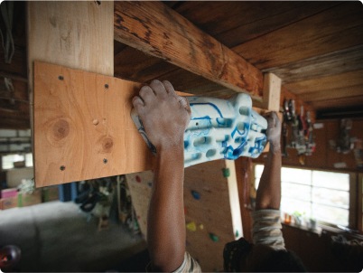 A climber practices their holds on a homemade climbing device in their garage.