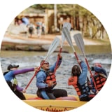4 people kayaking with their paddles in celebration