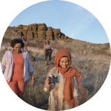 3 people walking with a geological structure behind them