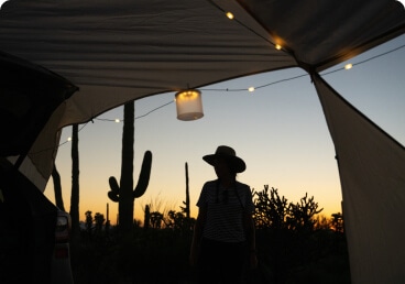 a person in a cowboy hat under a tent at dusk