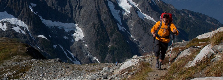 A hiker traverses a rocky alpine mountain pass