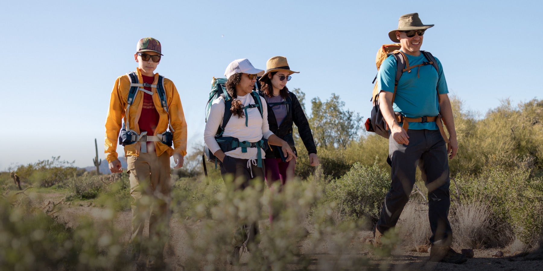 A group of hikers walk along a grassy trail