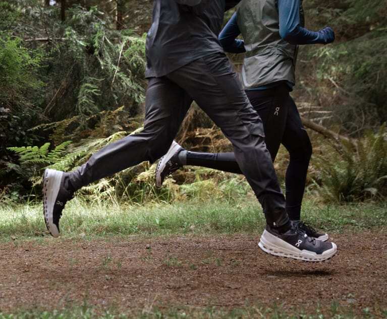 Two people, shown from the waist down, jog in unison on a tree-lined path
