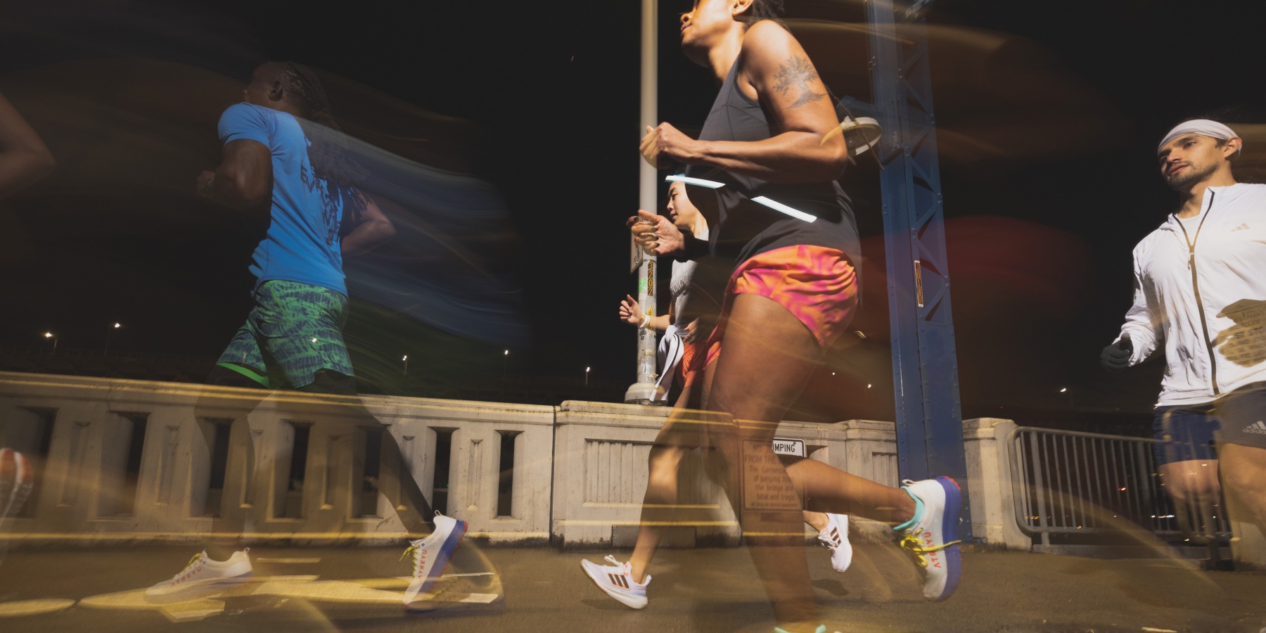 Runners on a bridge at night.