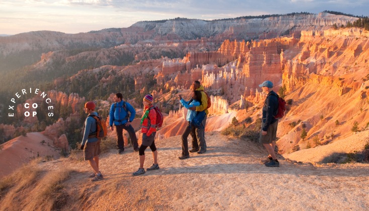 Hikers watching the sun rise over Bryce Canyon.