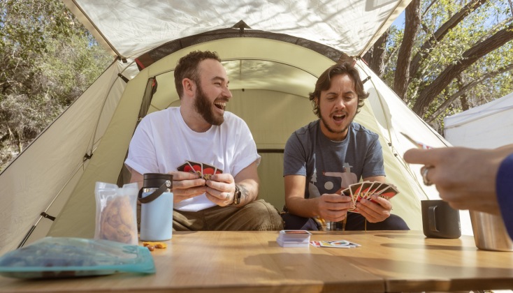 A view of the interior of a tent. Two campers sit on camp chairs near the tent's entrance.