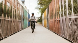 A cyclist cruises over an urban bike bridge.