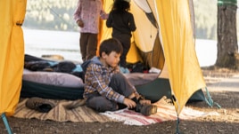 With sunshine lighting up their tent, three kids greet the morning after a good night's sleep.