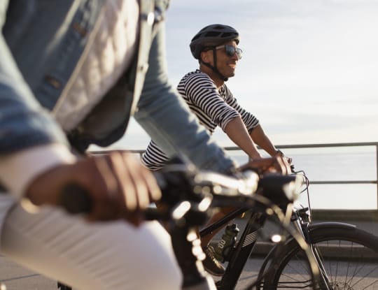 Two bikers riding on a boardwalk