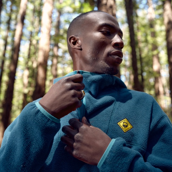 A person zips up their fleece jacket from the Outdoor Afro Inc. + R E I Co-op collection.