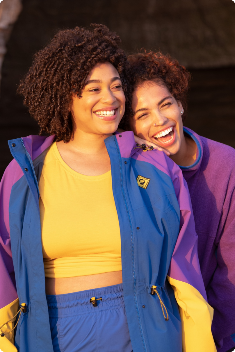 Two people smiling and wearing the Outdoor Afro Incorporated and R E I Co-op collection.