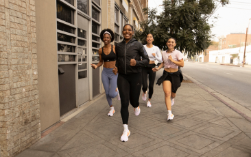 A group of runners jogs through a city setting.