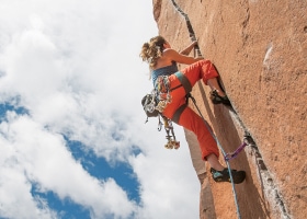 A climber jams their hands and feet into a crack as they work their way up a steep rock face.