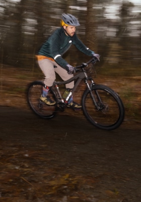 A mountain biker riding on a wooded trail.