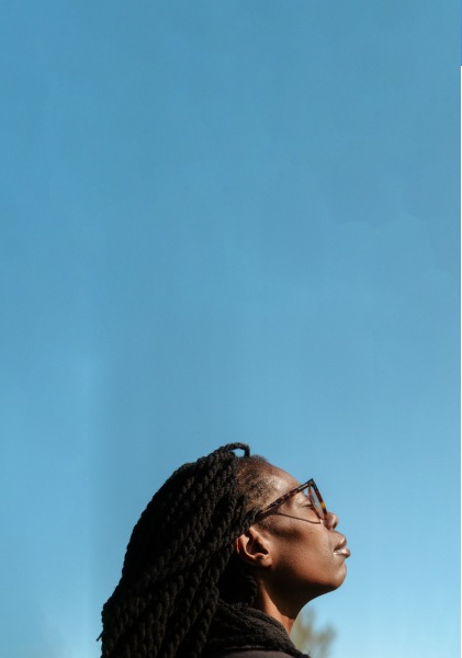 A person closing their eyes, feeling the sun on their face amidst endless blue sky.