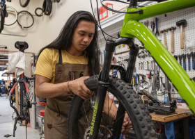 A shop services technician repairs a flat tire.
