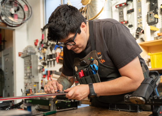 A shop services technician waxes a ski.