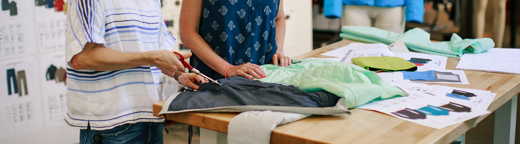 Two REI Co-op designers working over a table on jacket designs.