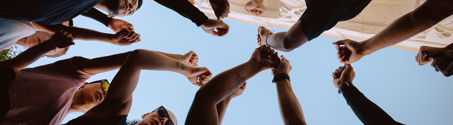 A group of people putting their fists together to hype each other up for a run in the city.