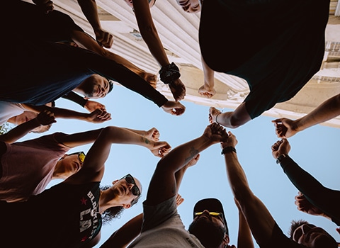 A group of people putting their fists together to hype each other up for a run in the city.