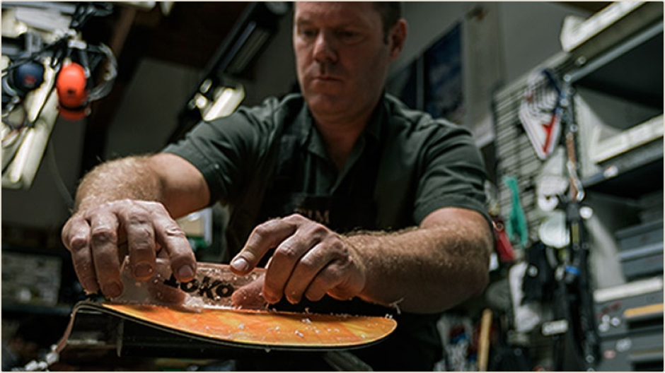 REI technician waxing a snowboard