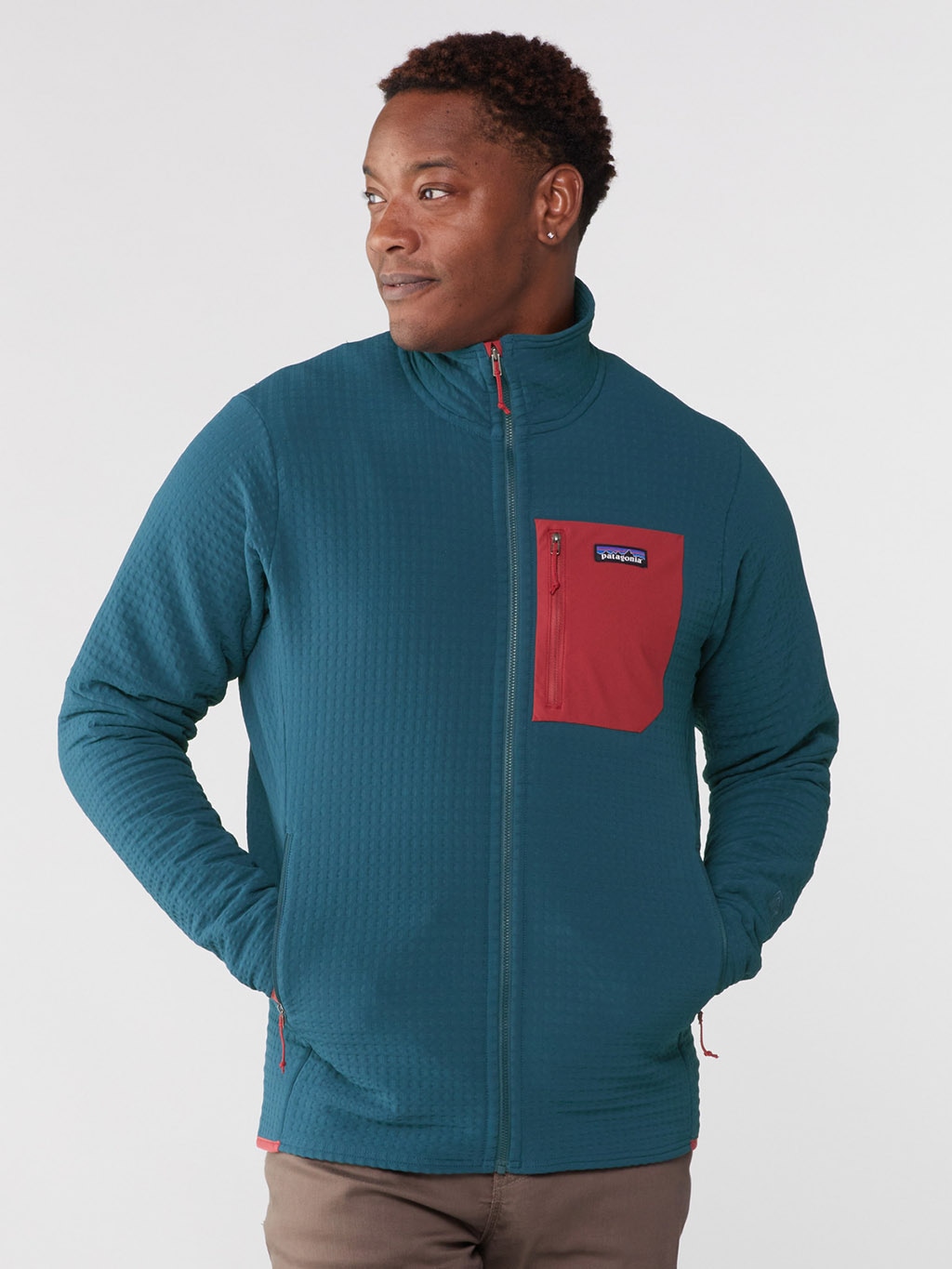 A Black person wearing a blue pullover with a red chest pocket