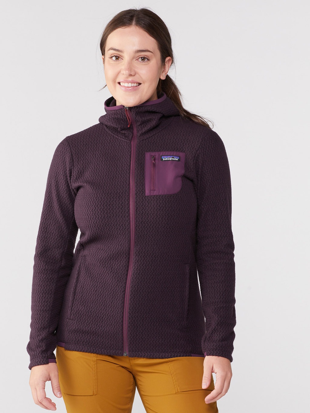 A white person wearing a dark purple pullover with a purple chest pocket