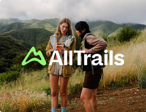 Two hikers checking the AllTrails app on a mountain trail