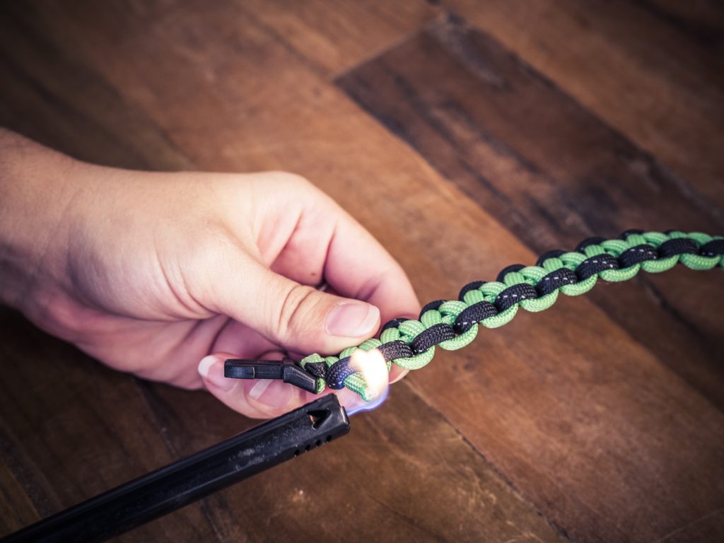 Paracord strand end being lit by a lighter