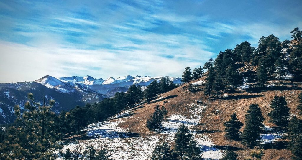 Snow covered mountains behind the foothills.