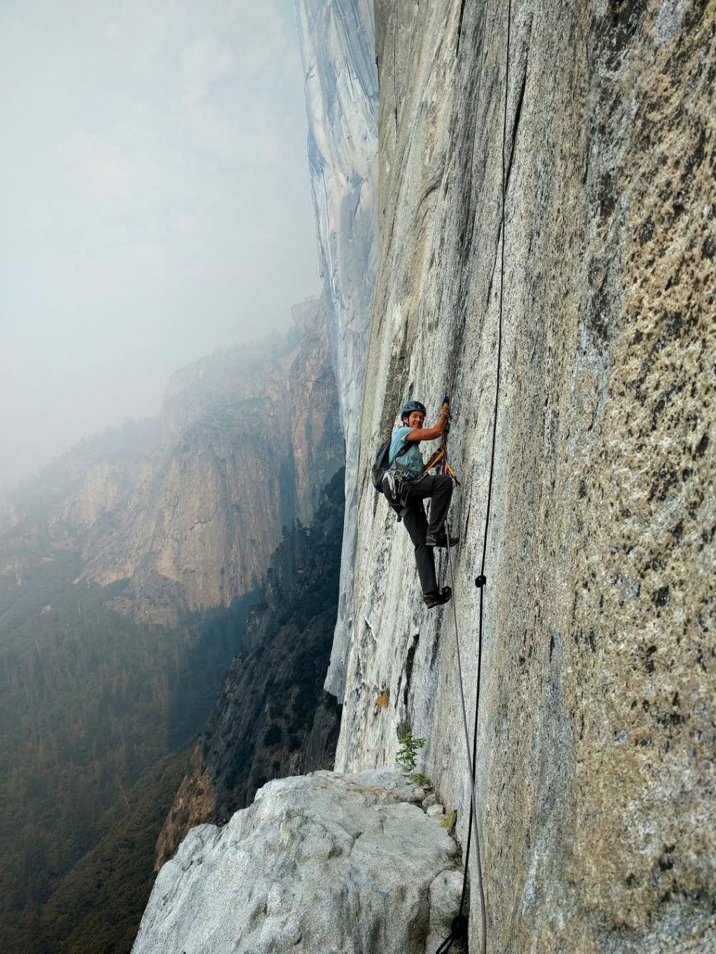 Diedre Wolownick uses jumars to ascend the steep rock face of El Capitan. Behind her, steel rock faces fade into the distance of Yosemite National Park.