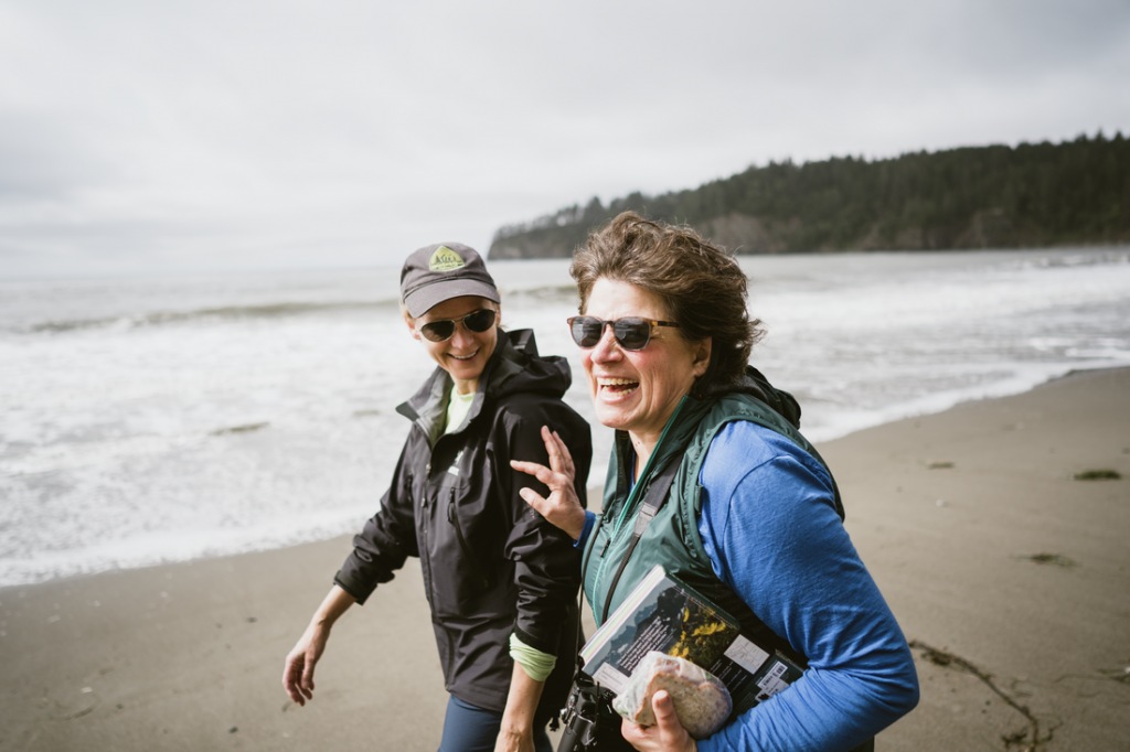 Two hikers laugh, one pushes the other one playfully.