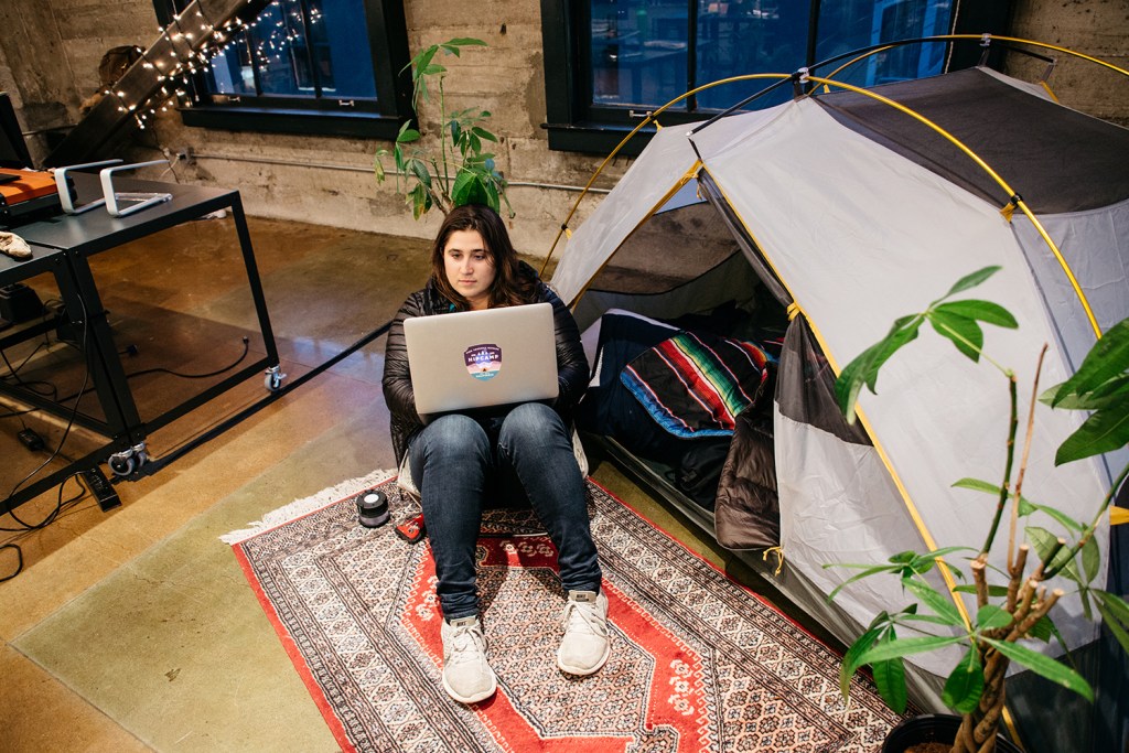 Alyssa Ravasio sitting programming by a tent