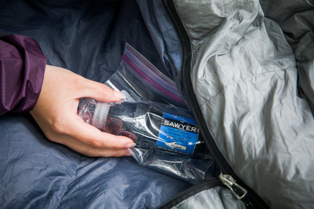 A water filter stored in a plastic bag inside a sleeping bag