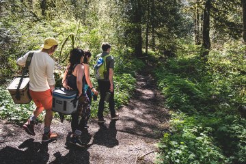 People on a trail carrying coolers
