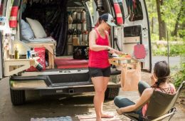 People preparing food in a van retrofitted with a kitchen.