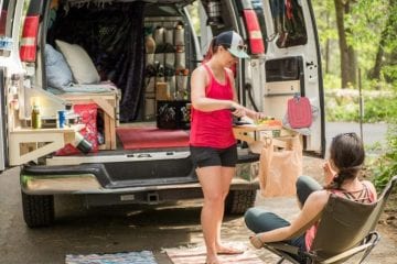 People preparing food in a van retrofitted with a kitchen.