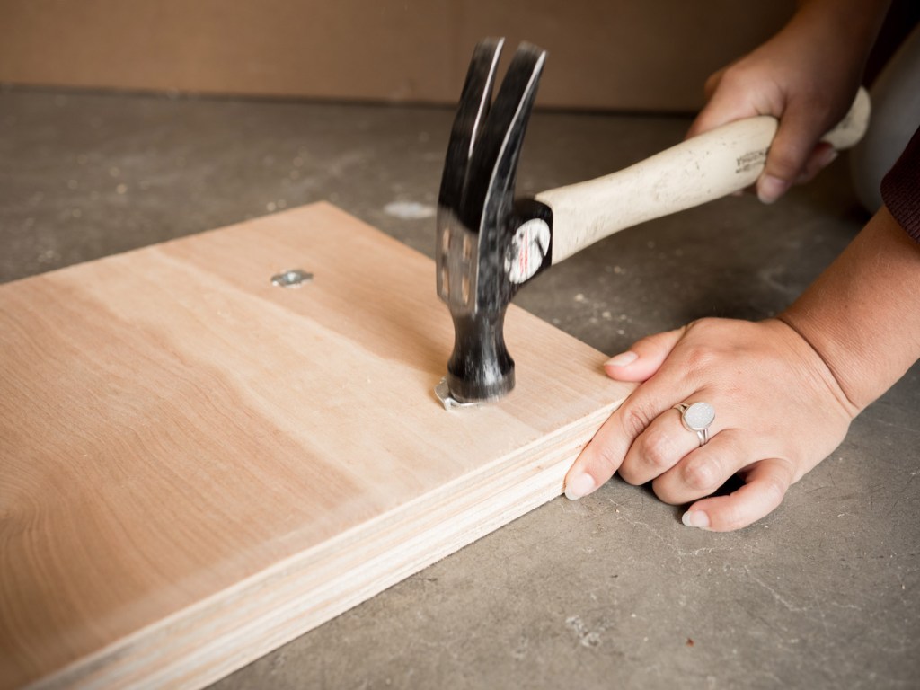 hammer the T-nut inserts into one side of the board until they’re flush with the wood