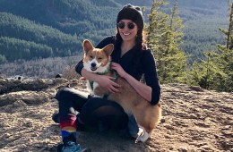 Corina sitting at the top of a hike with her corgi.