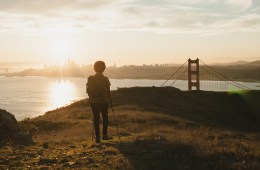 A hiker stands on a bluff overlooking San Francisco.