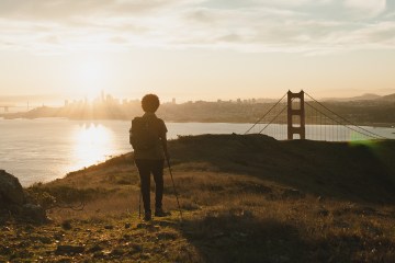 A hiker stands on a bluff overlooking San Francisco.