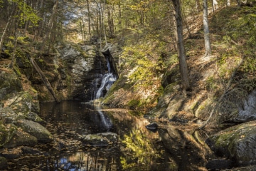 A forest in Granby, Connecticut with large rocks and a waterfall
