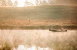 A woman paddling a canoe through a misty lake