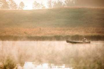 A woman paddling a canoe through a misty lake