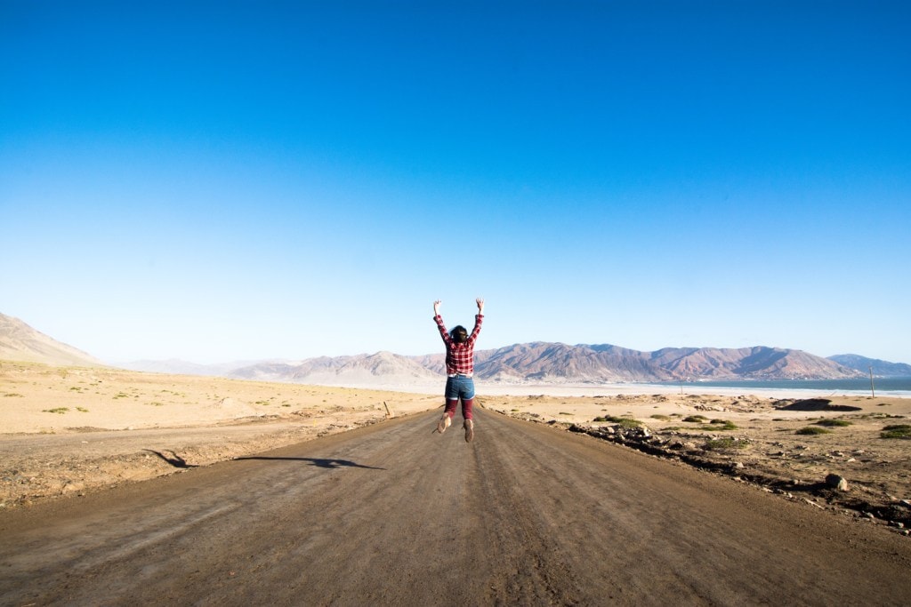 Woman jumping at the road Ataca Desert